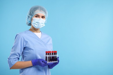 Photo of Laboratory testing. Doctor with blood samples in tubes on light blue background, space for text