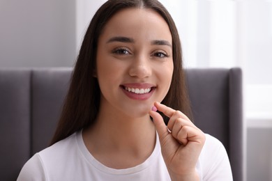 Photo of Beautiful young woman taking pill at home