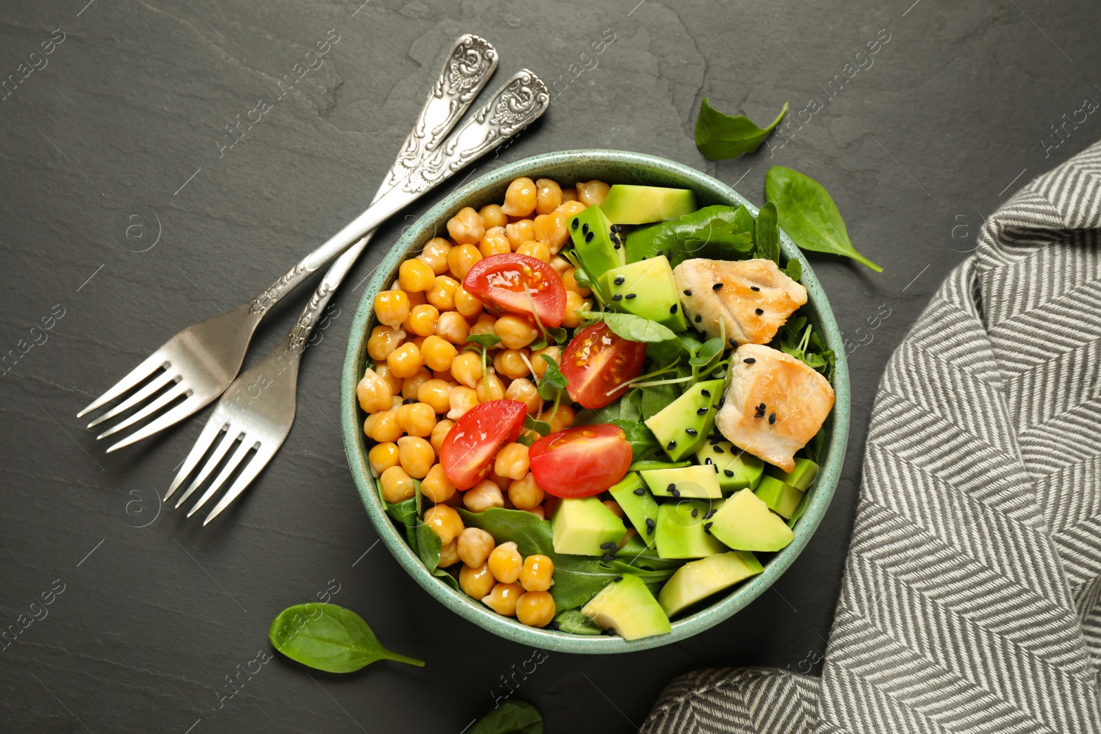 Photo of Delicious avocado salad with chickpea on black table, flat lay