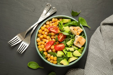 Delicious avocado salad with chickpea on black table, flat lay