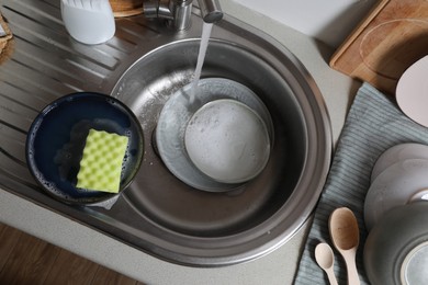 Photo of Washing plates in kitchen sink, above view