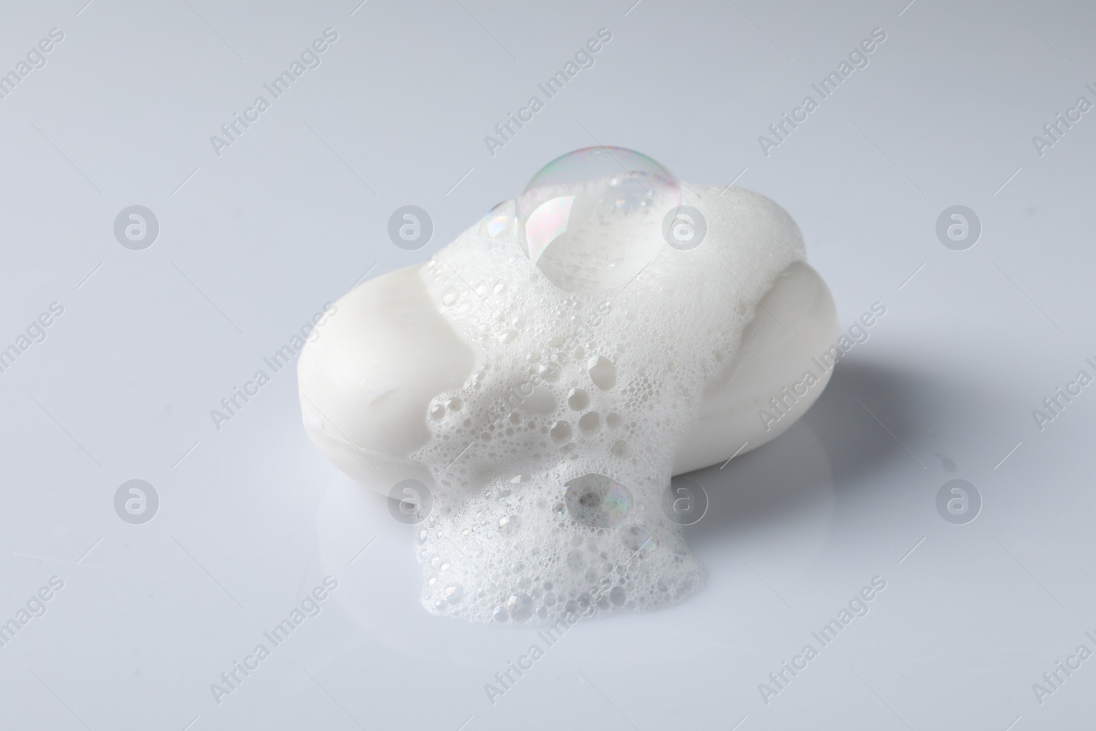 Photo of Soap with fluffy foam on white background