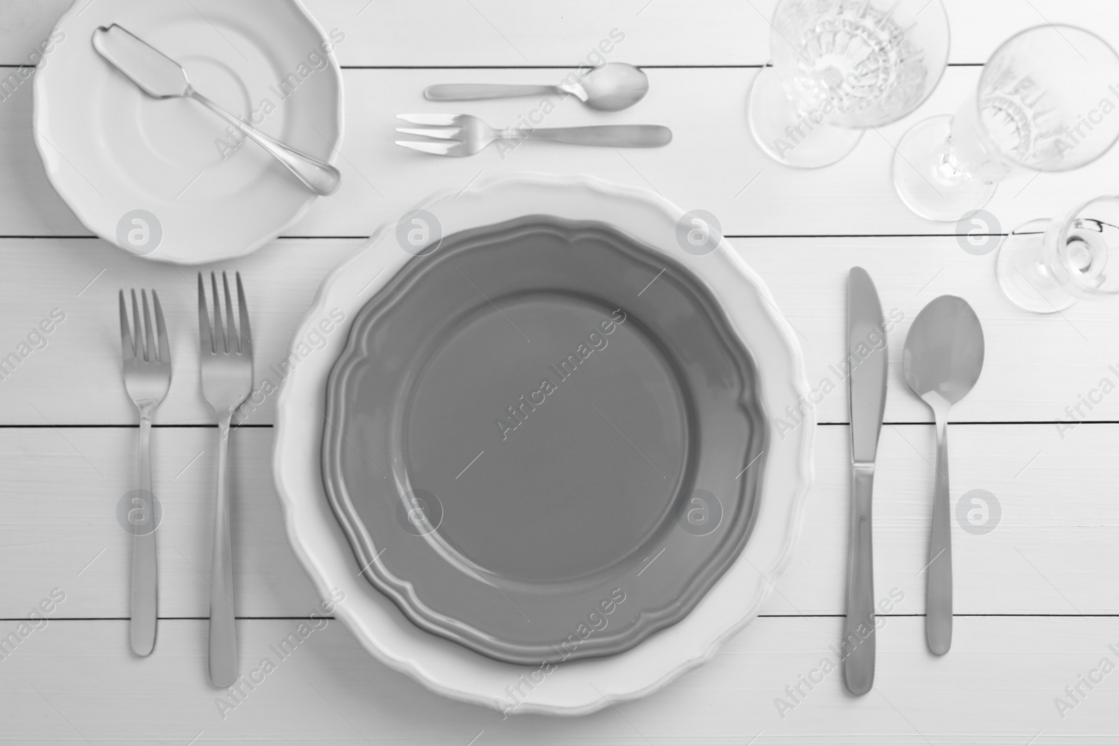 Photo of Stylish setting with cutlery, glasses and plates on white wooden table, flat lay