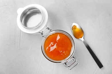 Jar and spoon with sweet jam on light background