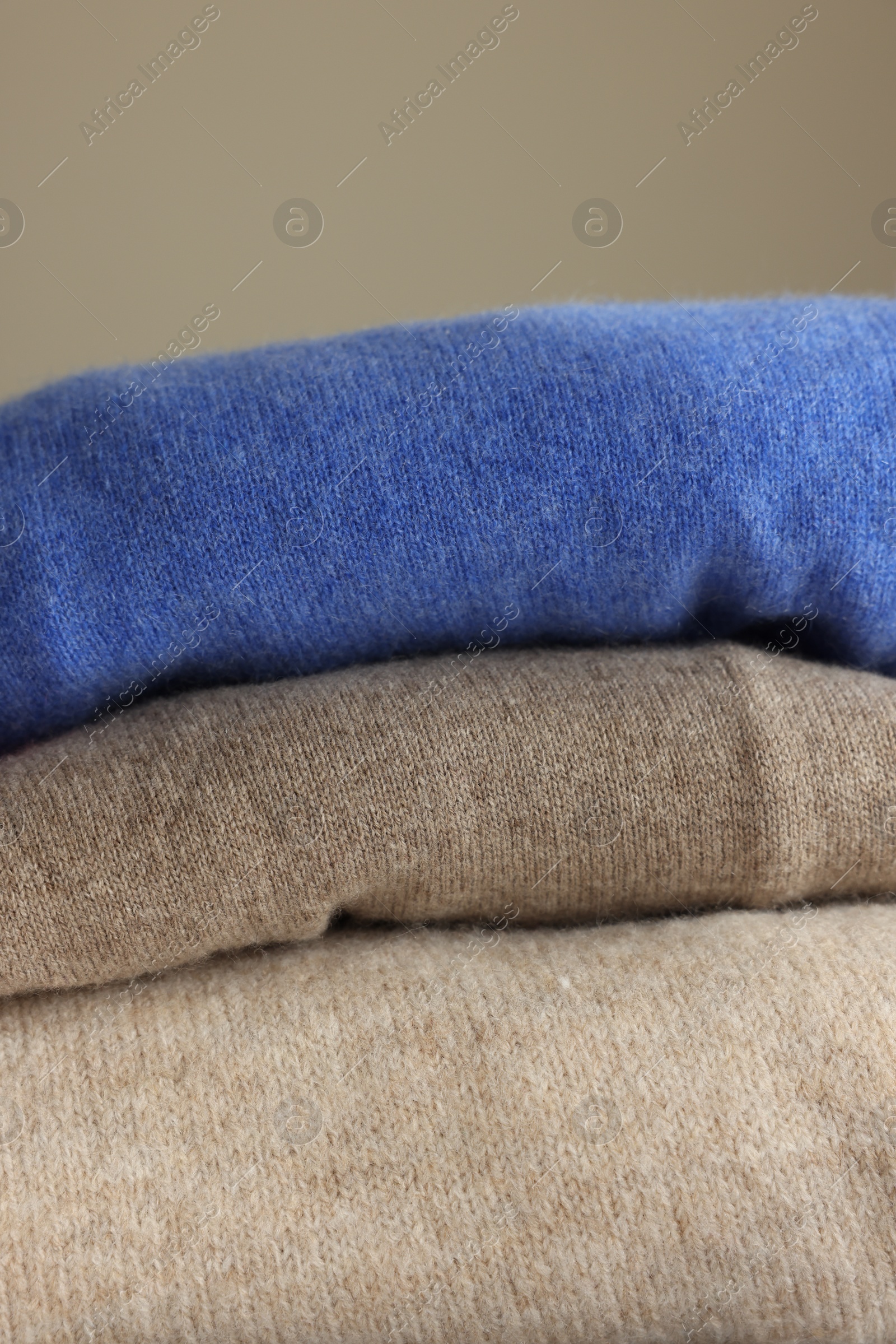Photo of Folded color sweaters on light background, closeup