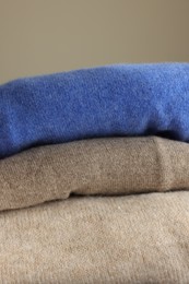 Photo of Folded color sweaters on light background, closeup