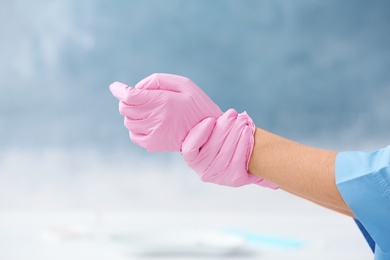 Photo of Doctor wearing medical gloves on color background