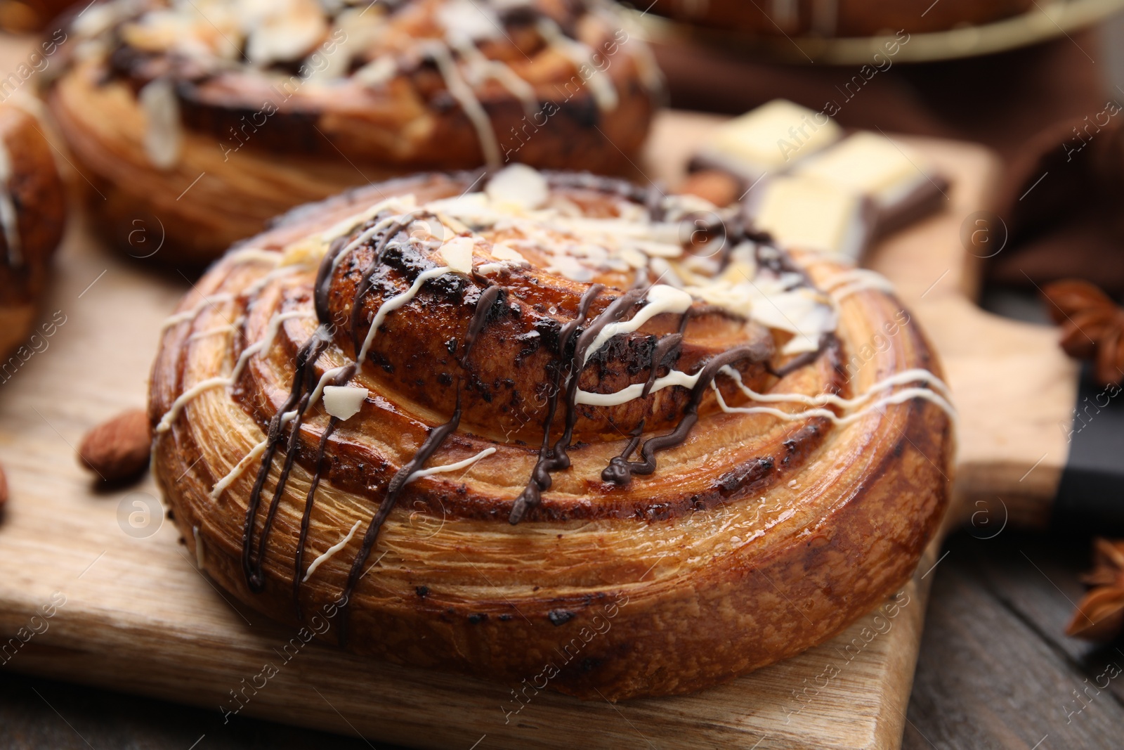 Photo of Delicious roll with toppings and nuts on wooden table, closeup. Sweet bun