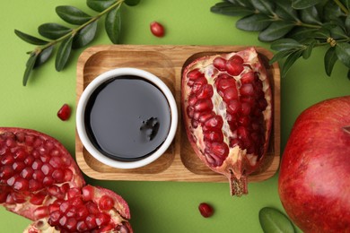 Photo of Flat lay composition with tasty pomegranate sauce and fruits on green table