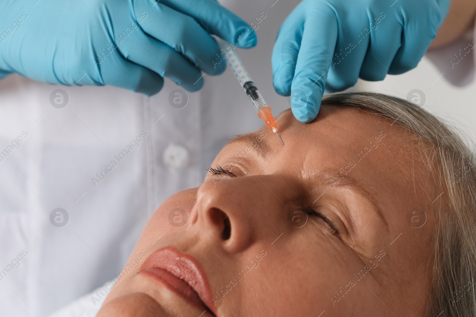 Photo of Doctor giving facial injection to senior woman in clinic, closeup. Cosmetic surgery