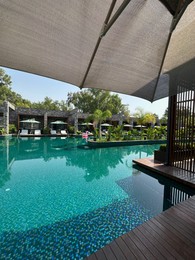 Swimming pool, exotic plants, umbrellas and sunbeds at luxury resort