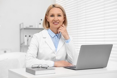 Photo of Portrait of happy dermatologist at white table in clinic