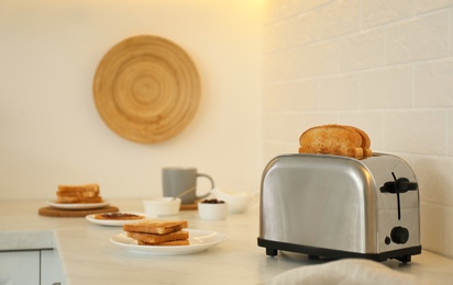 Modern toaster and tasty breakfast on counter in kitchen