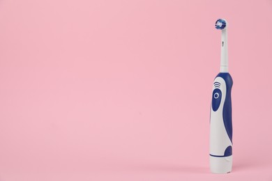 Photo of Electric toothbrush on pink background, space for text