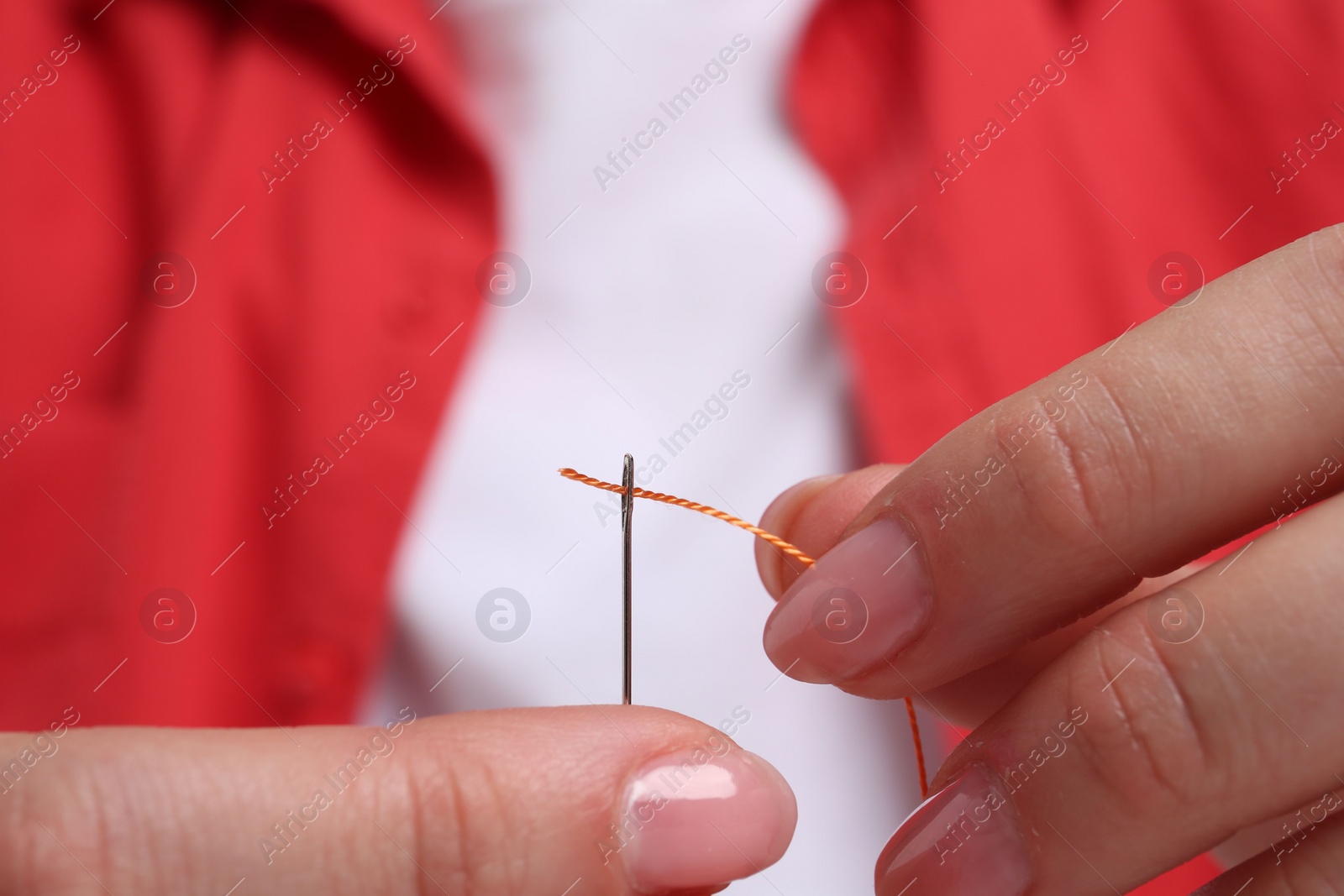 Photo of Woman inserting thread through eye of needle, closeup