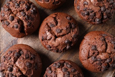 Photo of Tasty chocolate muffins on wooden board, flat lay