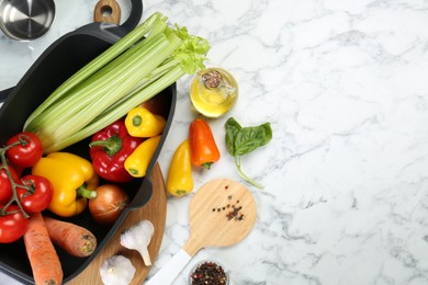 Photo of Black pot with round spatula and different products on white marble table, flat lay. Space for text