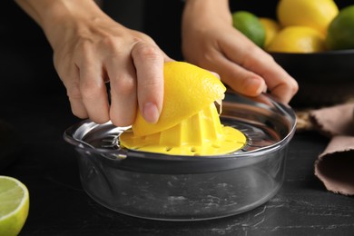 Photo of Woman squeezing lemon juice at black table, closeup