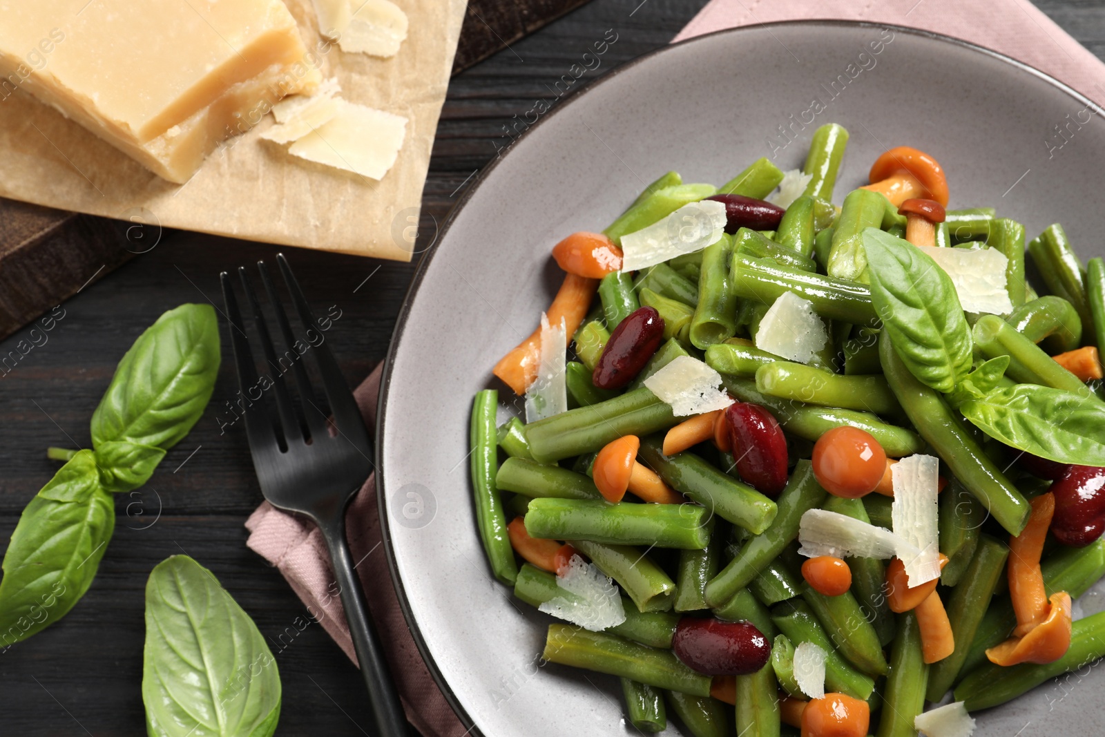 Photo of Delicious salad with green beans, mushrooms and cheese served on black wooden table