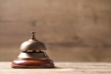 Hotel service bell on wooden table. Space for text