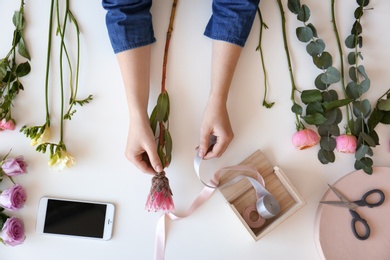 Female florist creating beautiful bouquet at table, top view