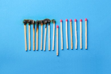 Burnt and whole matches on light blue background, flat lay