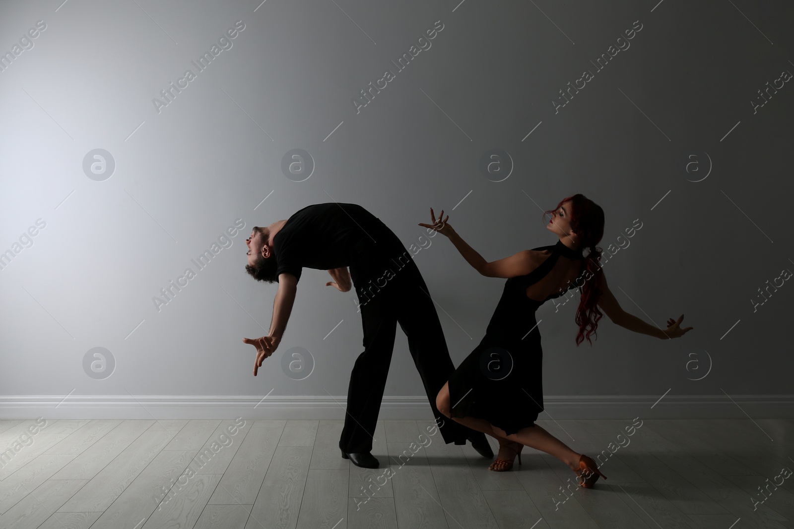 Photo of Beautiful young couple dancing near light wall