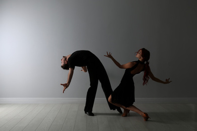 Beautiful young couple dancing near light wall