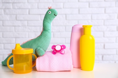 Baby accessories on table near white brick wall