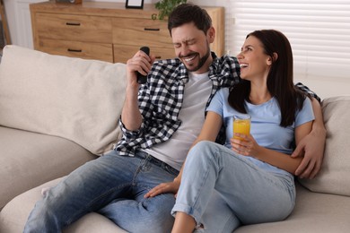 Photo of Couple watching comedy via TV and laughing at home
