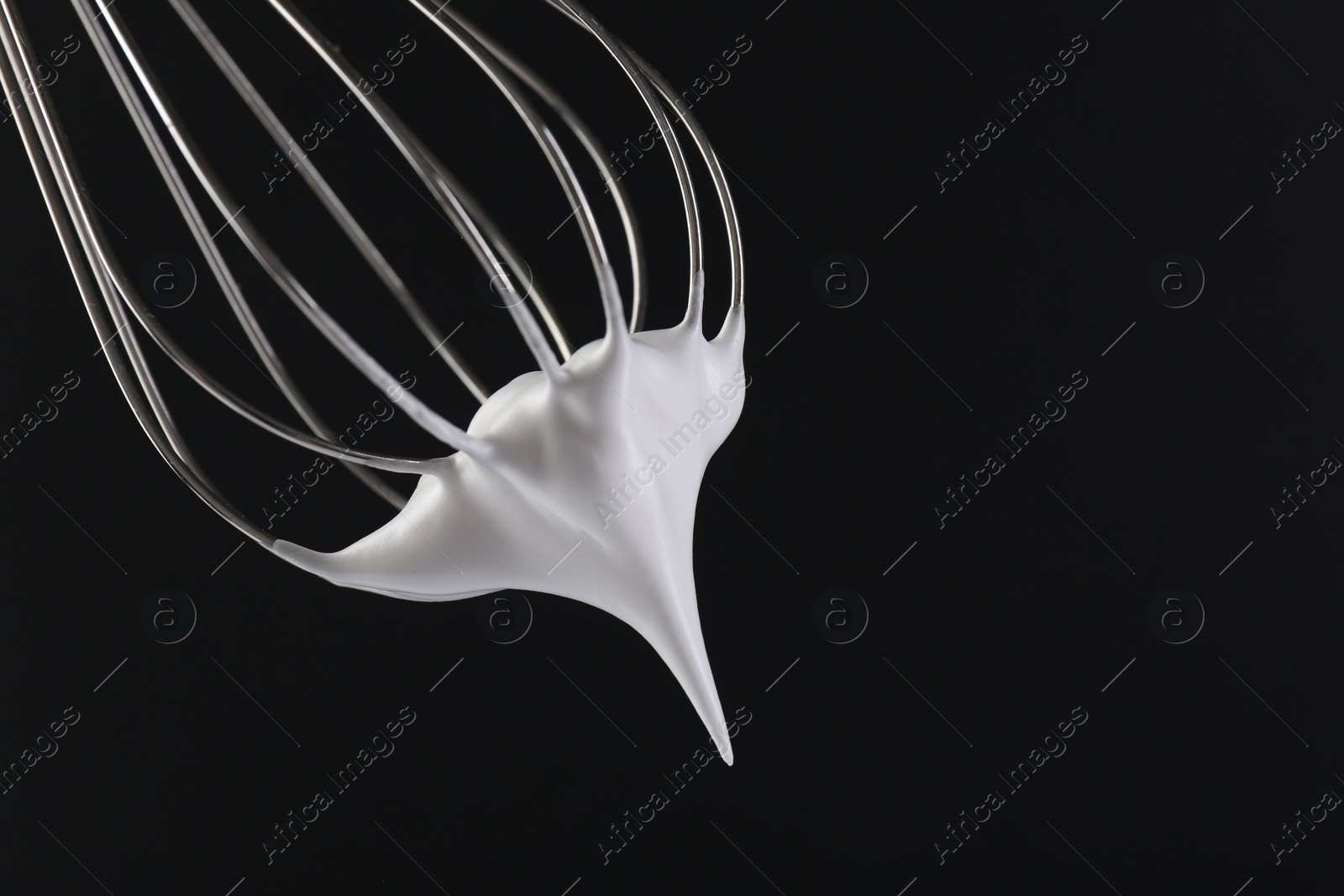 Photo of Whisk with whipped cream on black background, closeup. Space for text