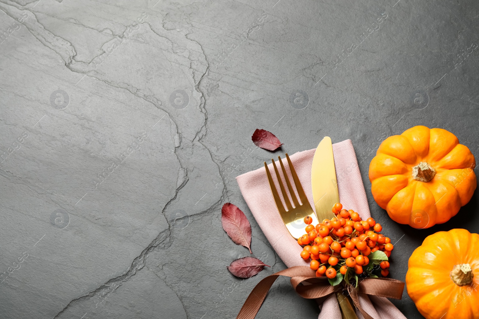 Photo of Cutlery, rowan berries and pumpkins on grey table, flat lay with space for text. Thanksgiving Day