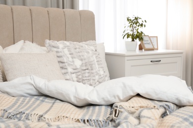 Photo of Bed with pillows and blanket in light room