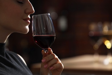 Photo of Woman with glass of red wine against blurred background, closeup. Space for text