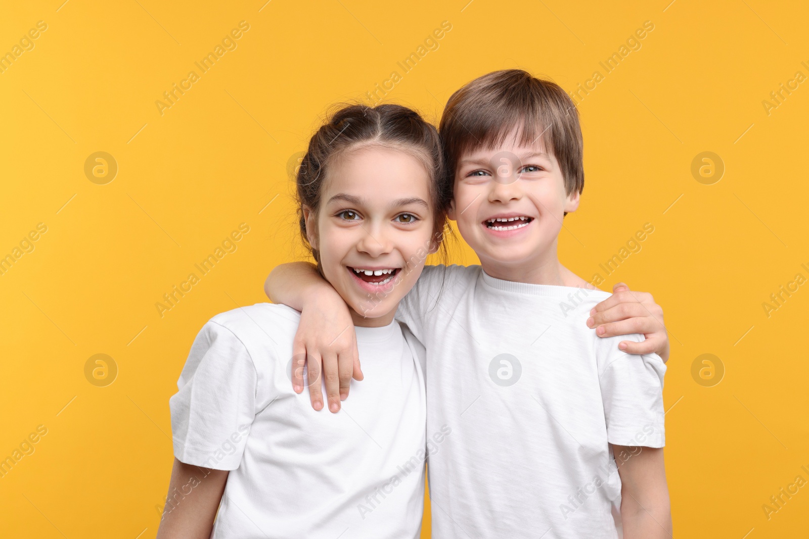 Photo of Happy brother and sister on orange background