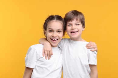 Happy brother and sister on orange background