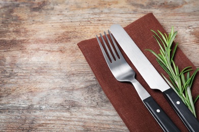 Photo of Fork, knife and napkin on wooden background. Space for text