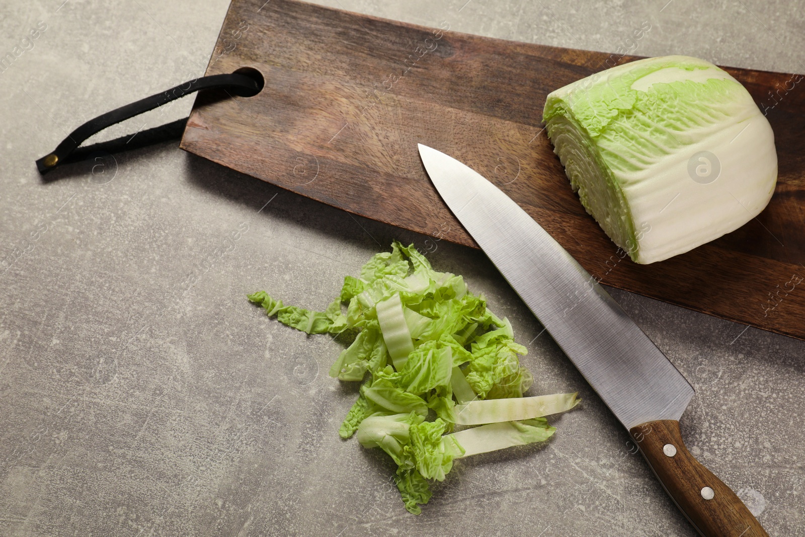 Photo of Cut fresh Chinese cabbage and knife on light grey table