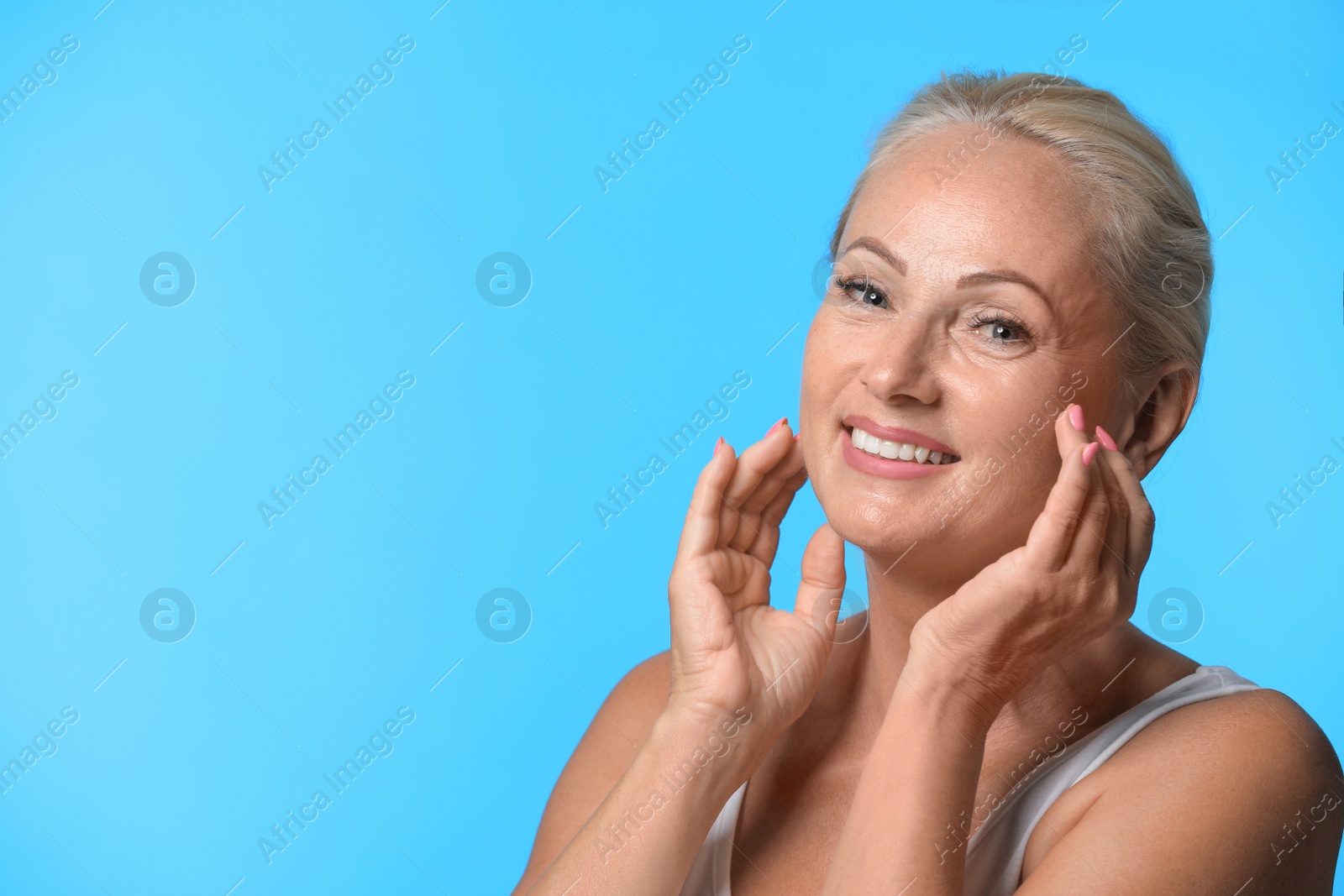 Photo of Portrait of beautiful mature woman with perfect skin on light blue background. Space for text