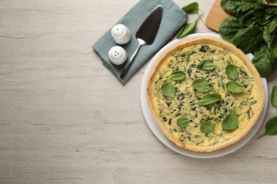 Delicious homemade spinach pie served on white wooden table, flat lay. Space for text