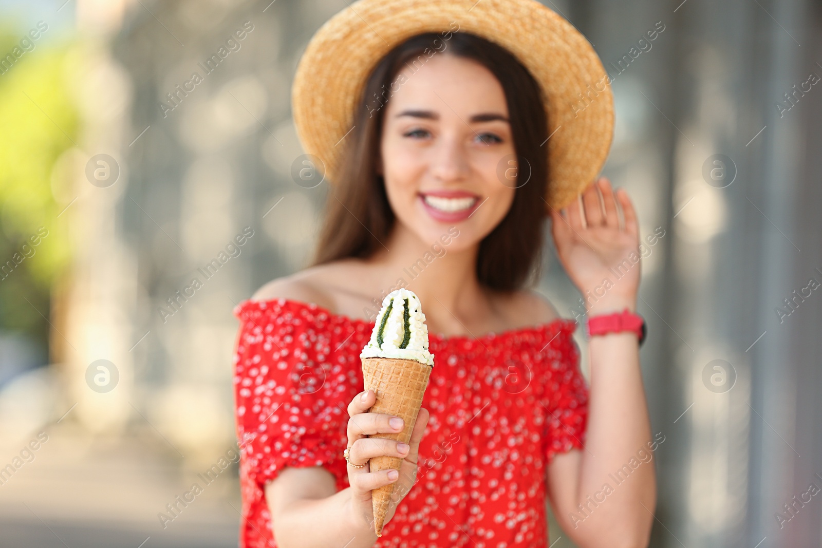 Photo of Happy young woman with delicious ice cream in waffle cone outdoors