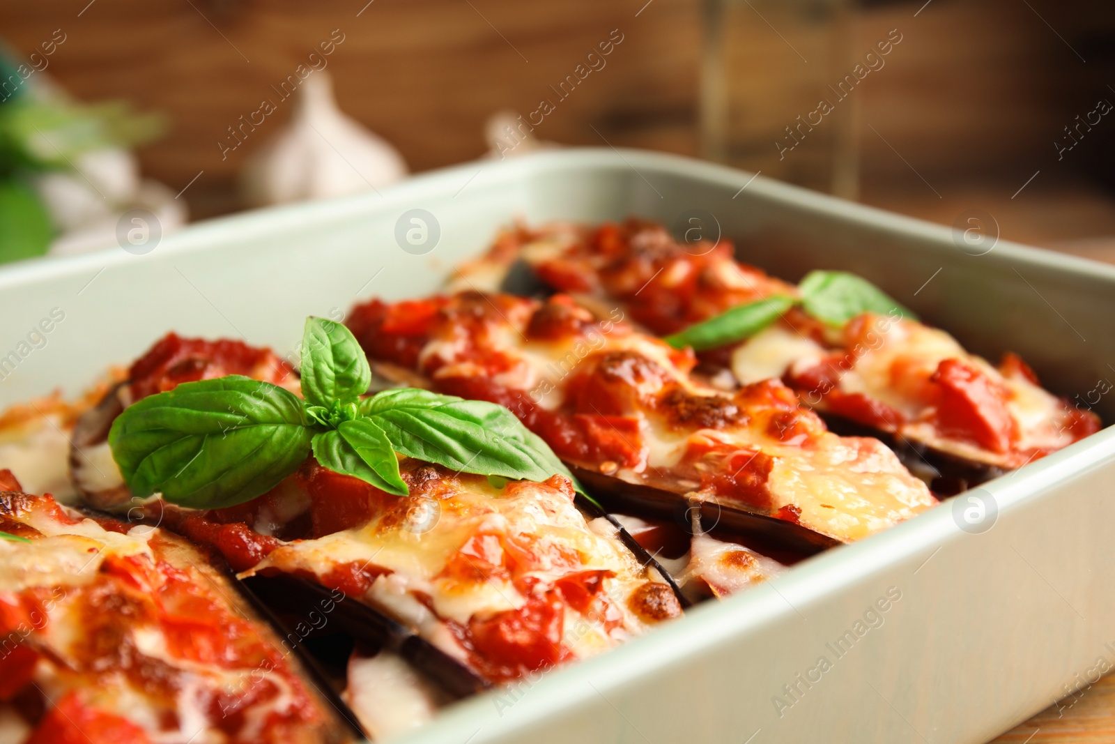 Photo of Baked eggplant with tomatoes, cheese and basil in dishware, closeup