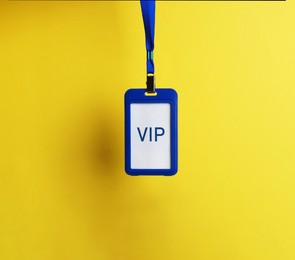 Photo of Blue plastic vip badge hanging on yellow background