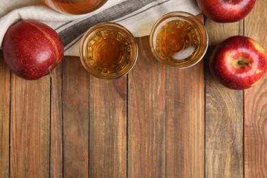 Delicious cider and ripe red apples on wooden table, flat lay. Space for text