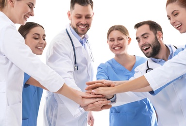 Team of medical doctors putting hands together on white background. Unity concept