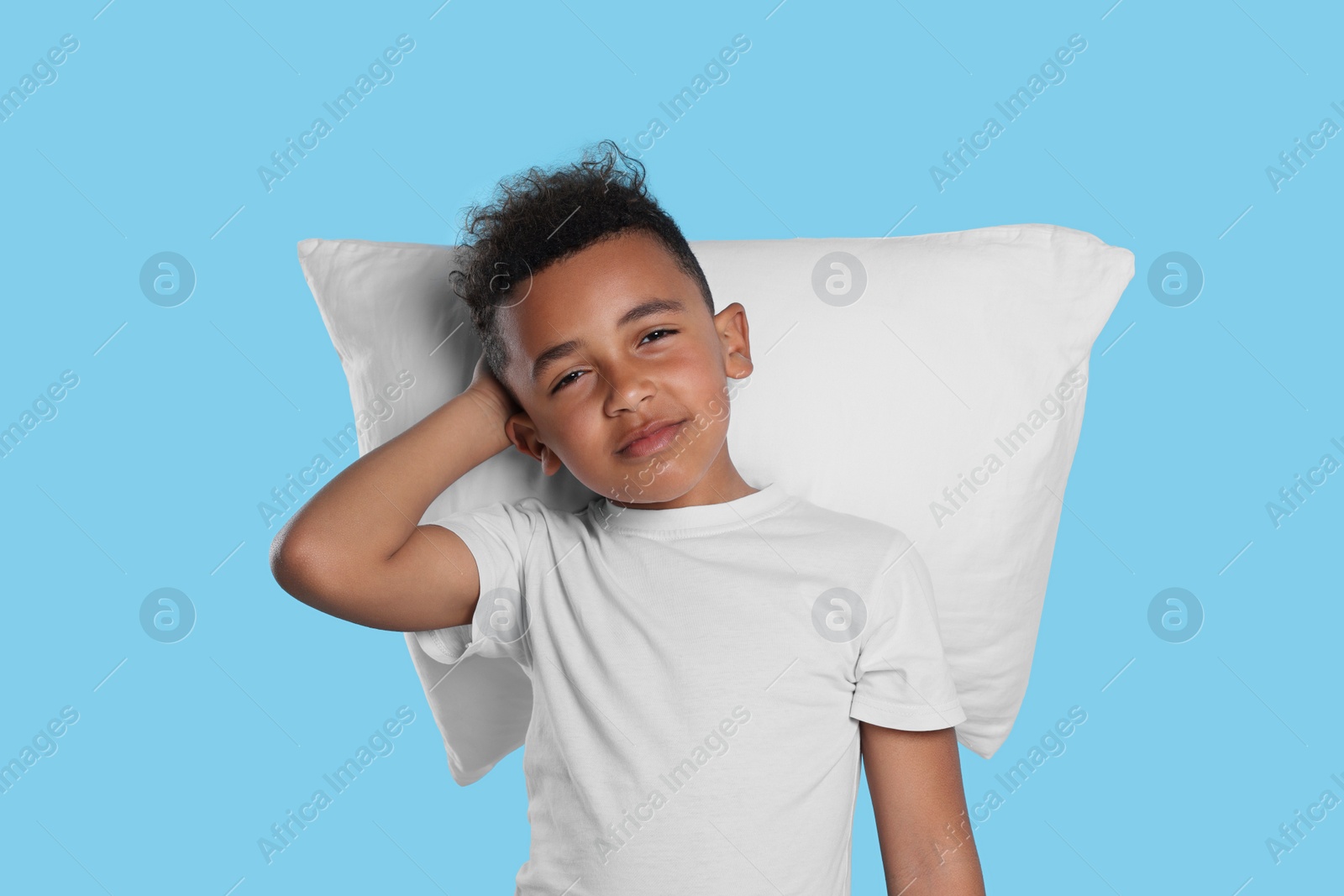 Photo of Boy with pillow on light blue background. Insomnia problem