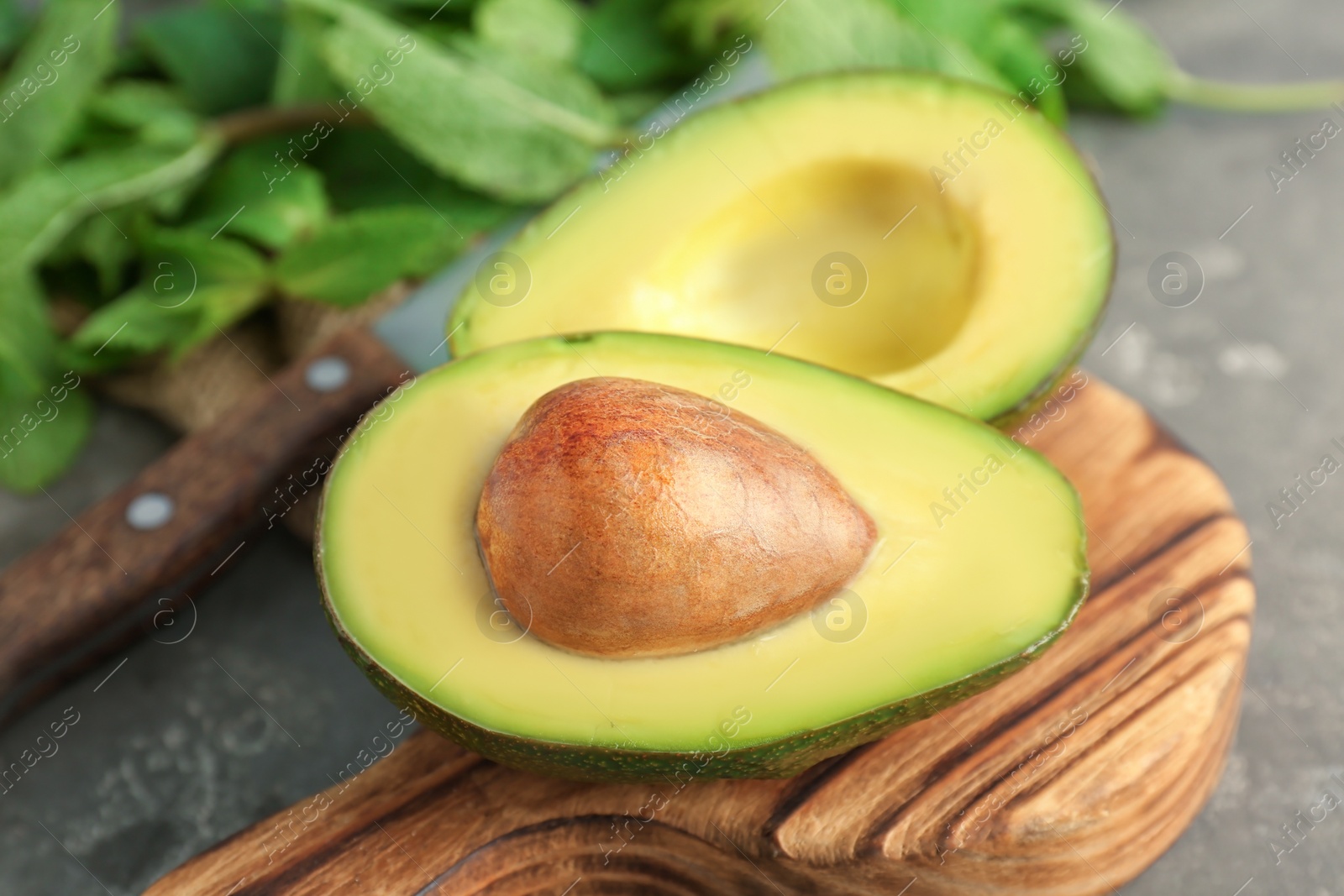 Photo of Wooden board with cut avocado on table, closeup