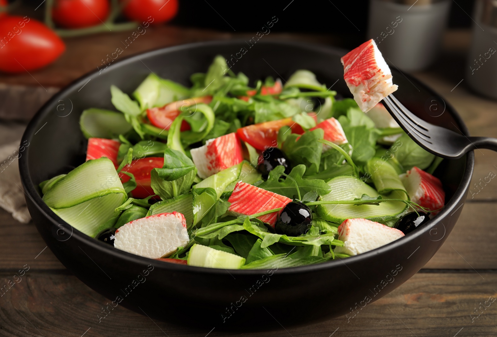 Photo of Delicious crab stick salad in bowl on wooden table, closeup