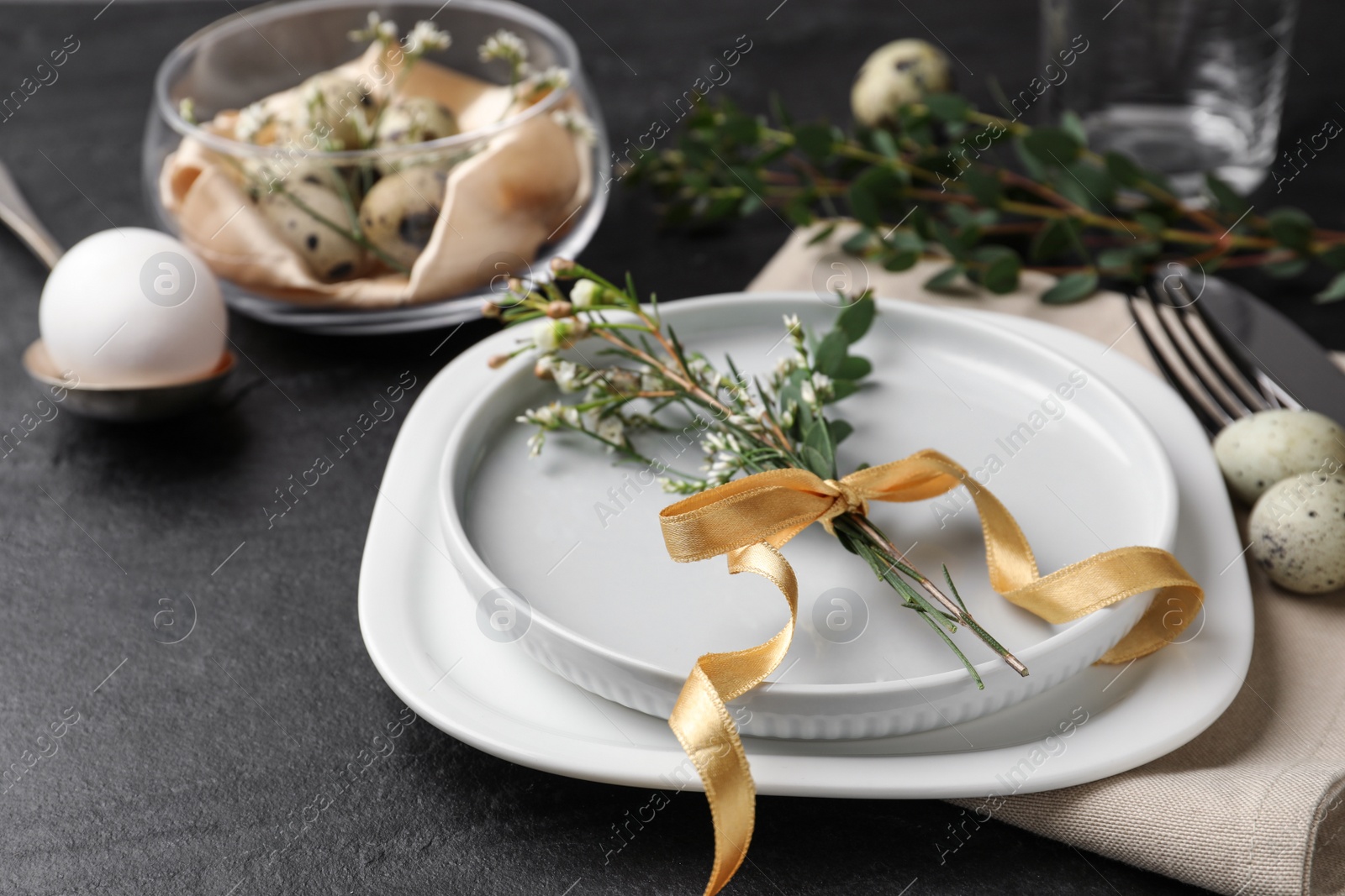 Photo of Festive Easter table setting with eggs and floral decoration on dark background, closeup