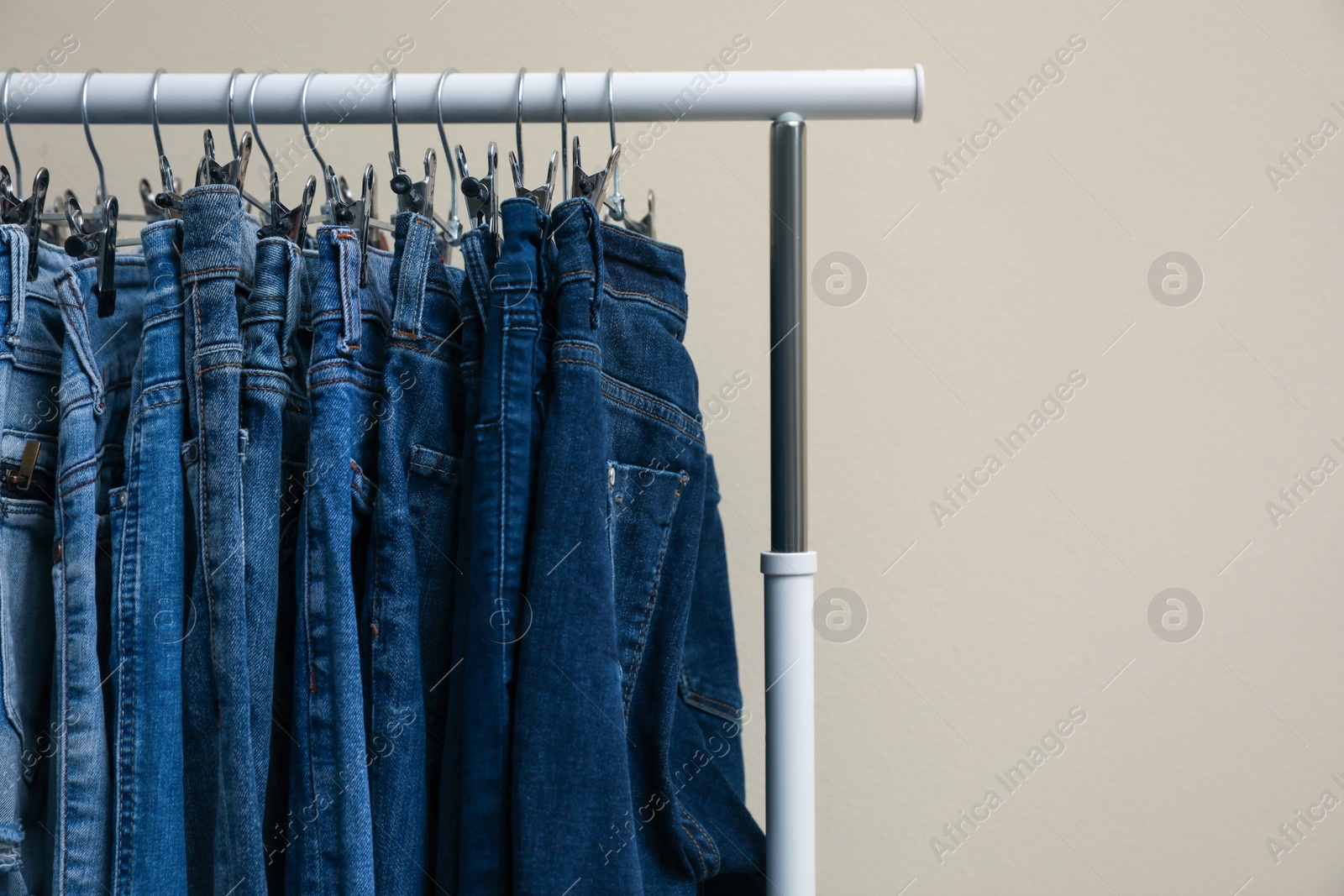 Photo of Rack with stylish jeans on color background, closeup